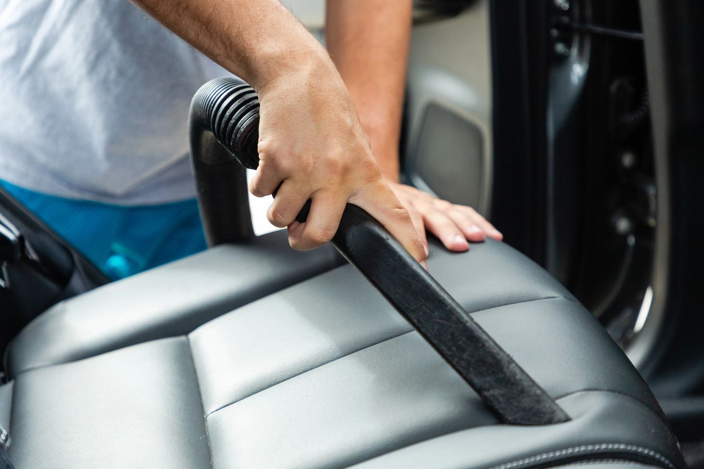 A person is using an electric razor to clean the seat of a car.