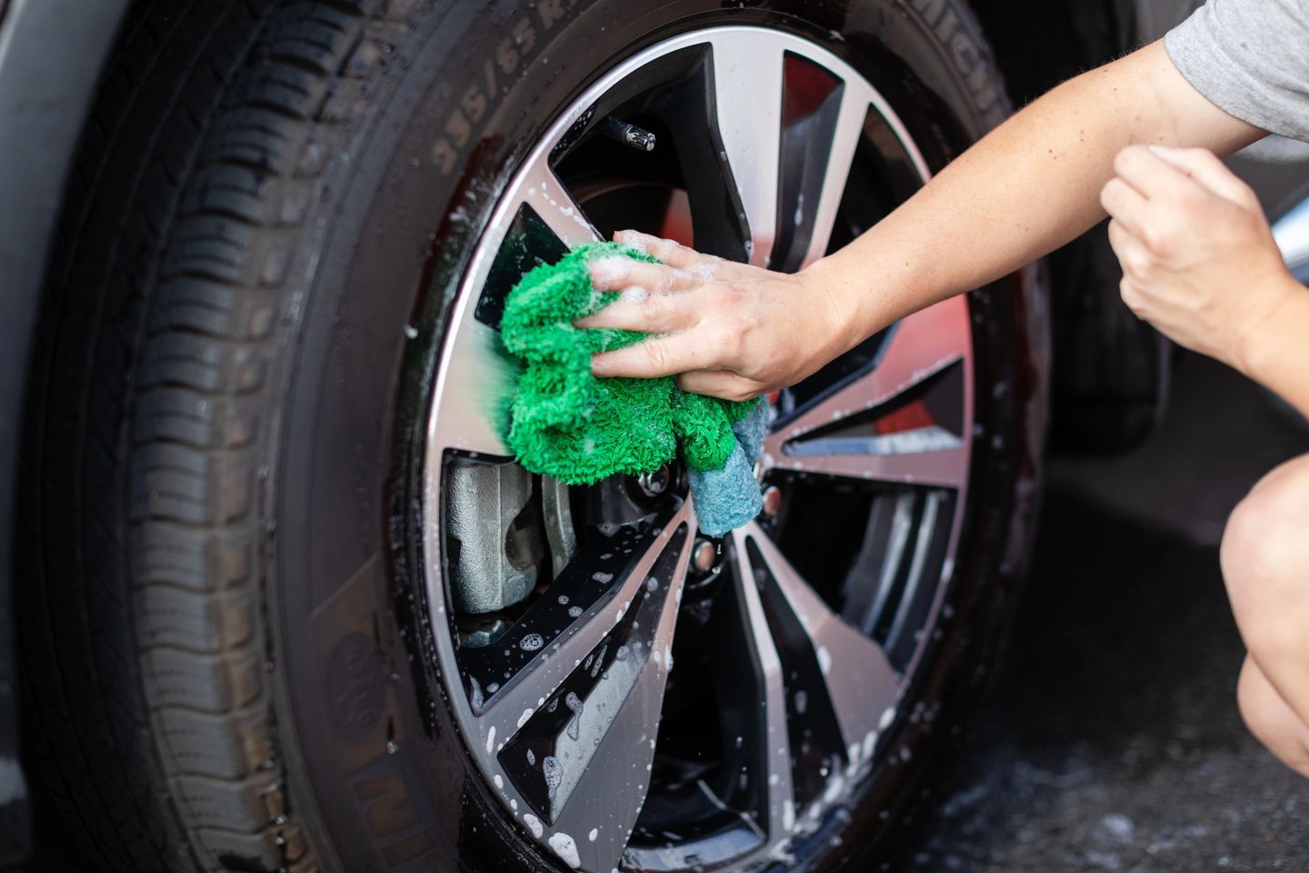 A person cleaning the wheel of a car